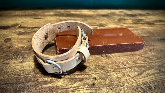 Detailed view of a natural vegetable-tanned leather cuff highlighting the authentic hide texture and intentional fit.