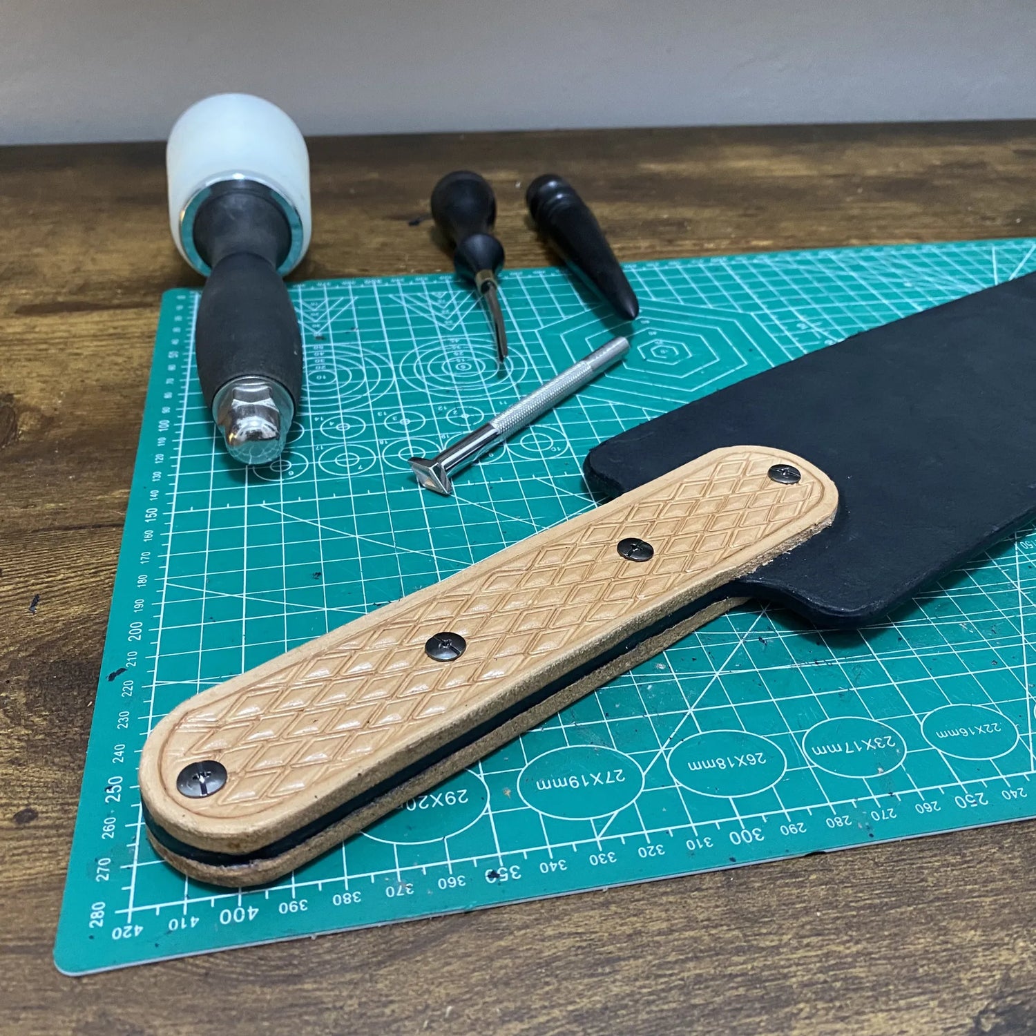 Scale detail showing handmade spanking strap beside a poly-maul hand tool.