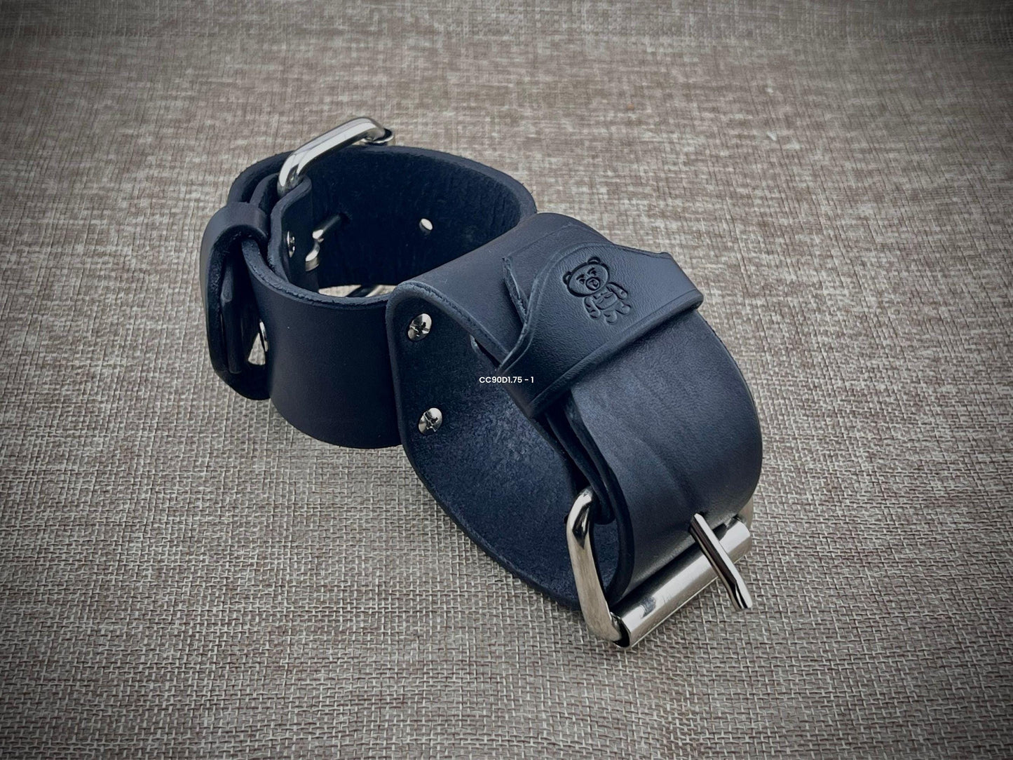 Black leather straps with metal buckle on a textured gray background