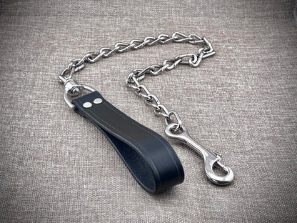 Black leather strap with metal chain and clasp on a textured gray background