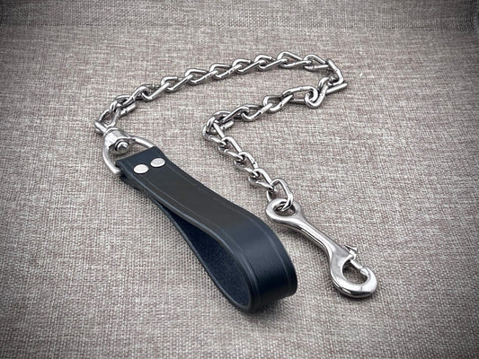 Black leather strap with metal chain and clasp on a textured gray background