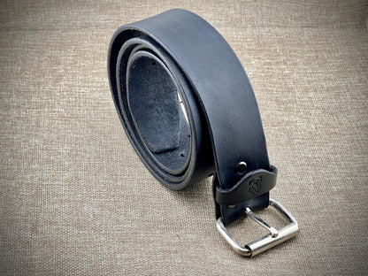 Black leather belt with steel buckle on a textured beige surface