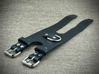 Black leather strap with steel buckles on a textured gray background