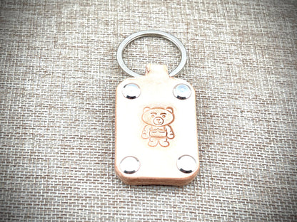 Leather keychain with teddy bear design on a textured fabric background