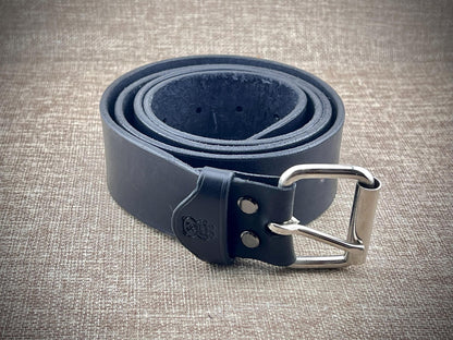 Black leather belt with a silver buckle on a textured beige background