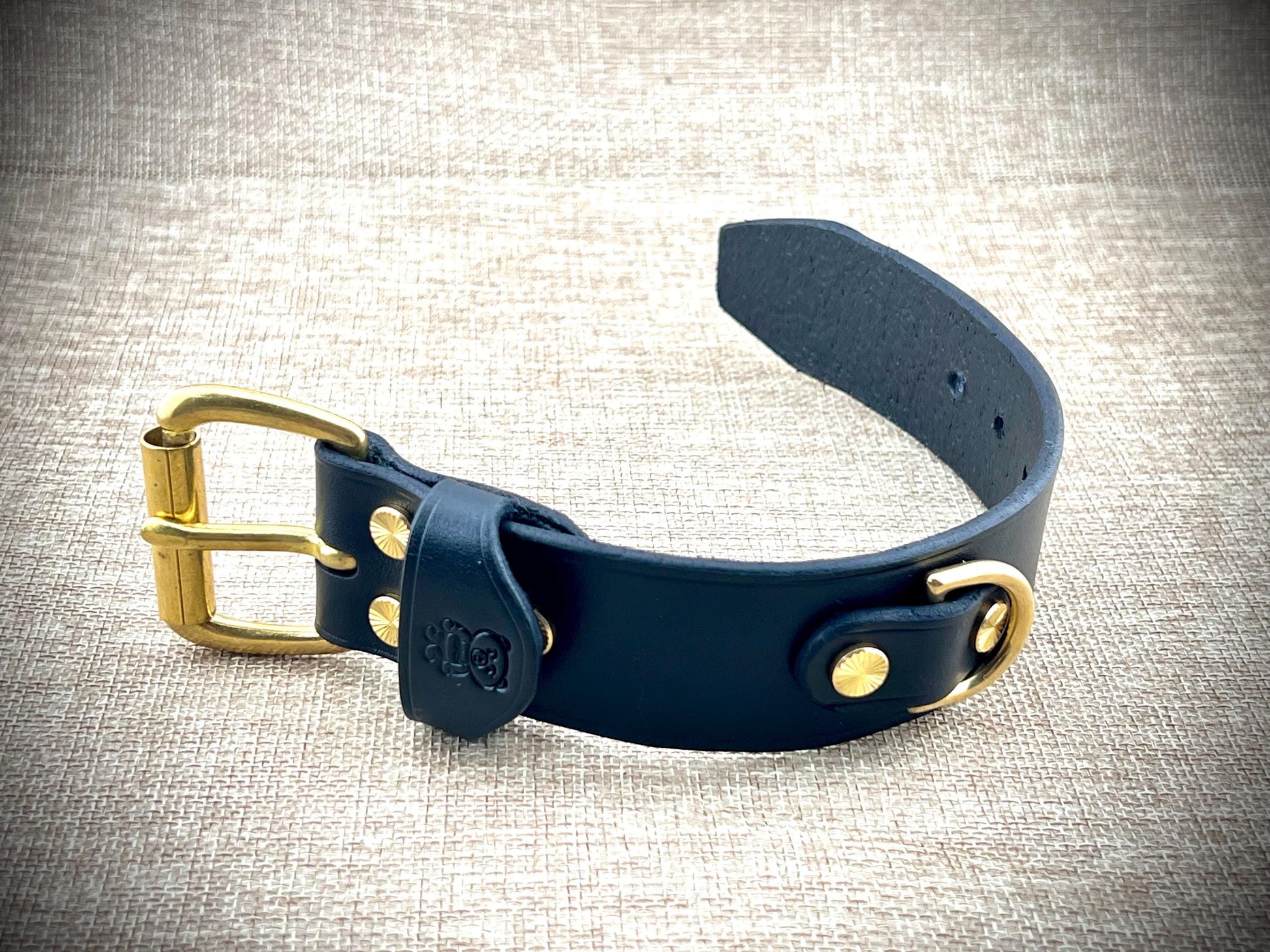 Black bracelet with brass hardware on a textured fabric background