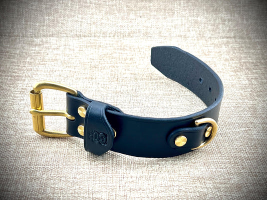 Black bracelet with brass hardware on a textured fabric background