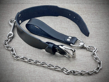Black leather collar with steel chain on a textured gray background