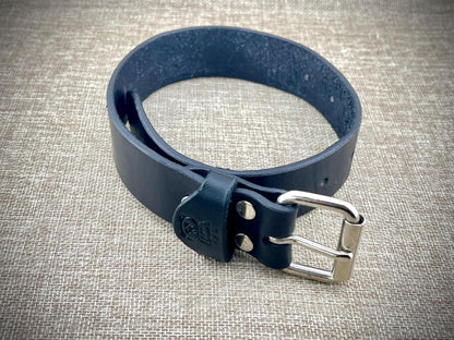Black leather belt with silver buckle on a textured gray background