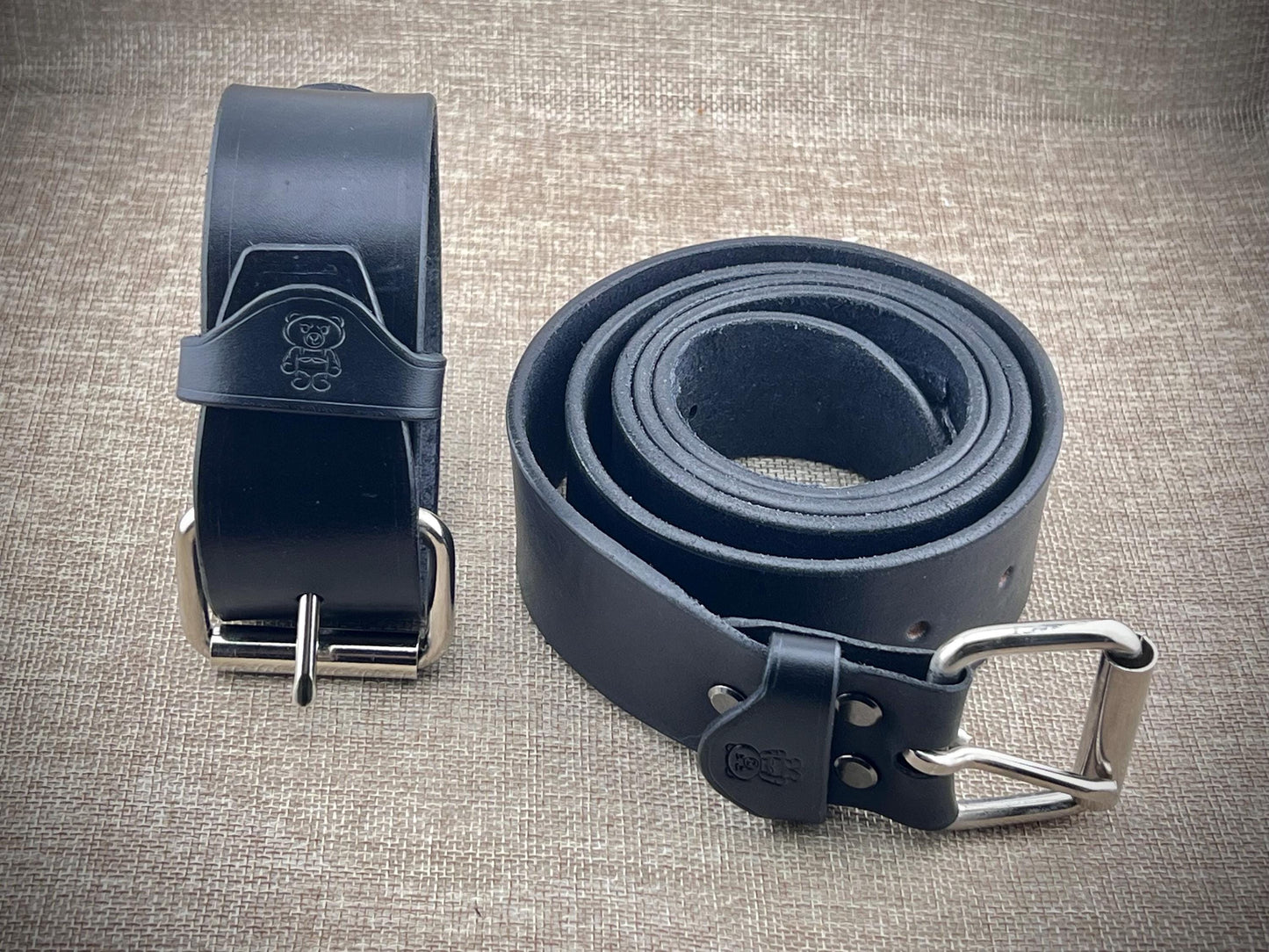 Black leather belt with steel buckle on a textured surface