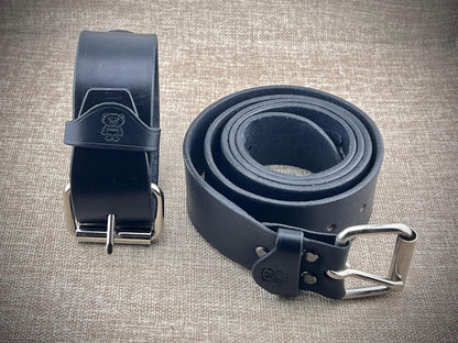 Black leather belt with steel buckle on a textured surface