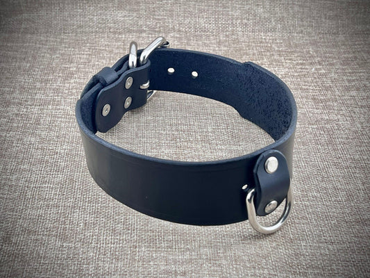 Black leather collar with metal hardware on a gray textured background