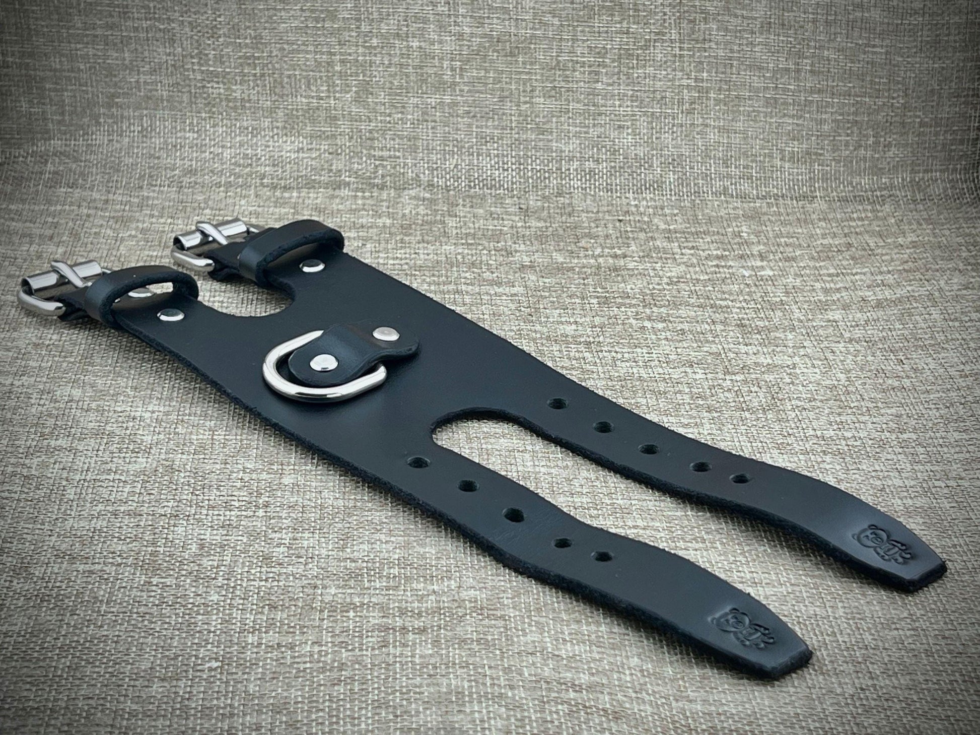 Black leather strap with silver buckle on a textured gray background