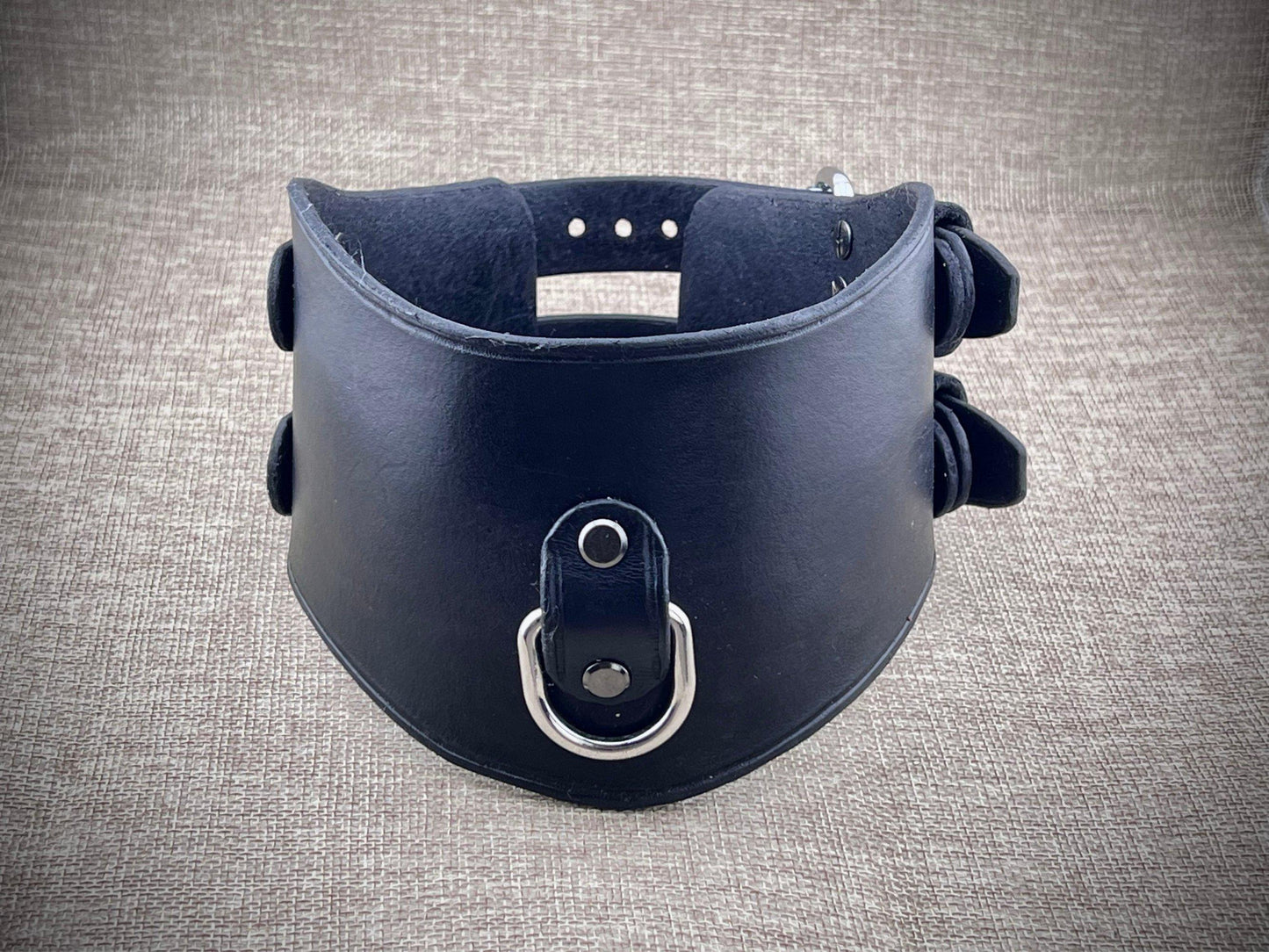 Black leather collar with metal ring on a gray textured background