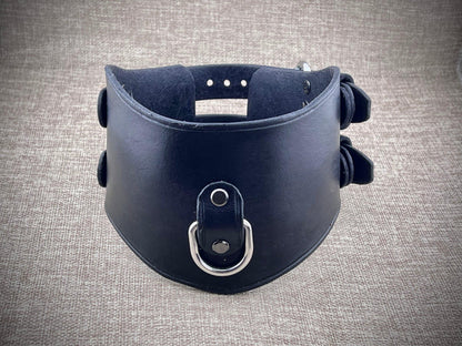 Black leather collar with metal ring on a gray textured background
