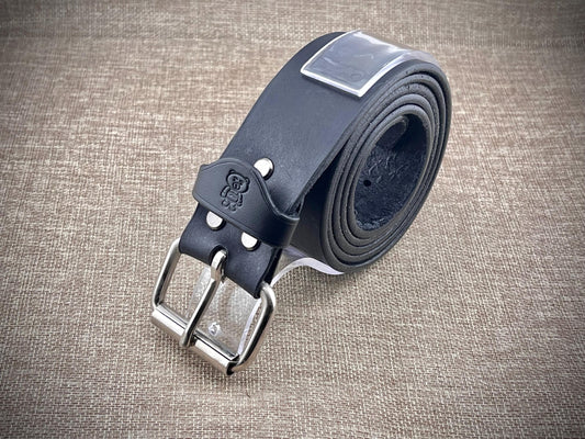 Black leather belt with silver buckle on a textured brown surface