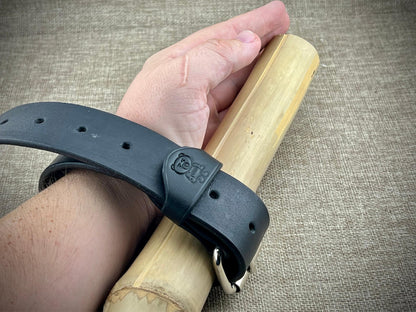 Hand wearing a black wristband holding a wooden object on a textured surface