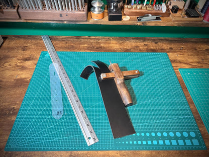 Crafting tools on a green cutting mat with a ruler