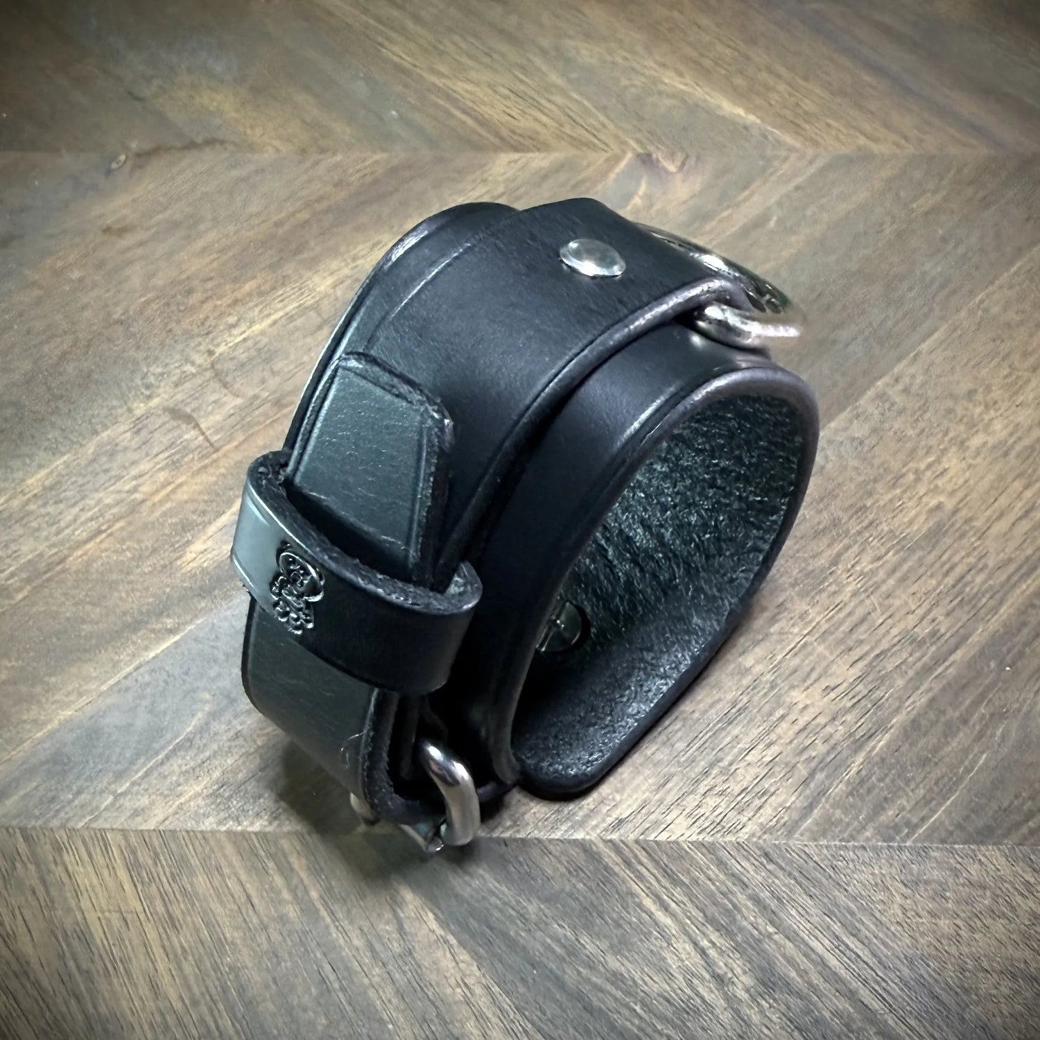 Three-quarter view of a handcrafted 1.75" black leather two-piece cuff showcasing premium vegetable-tanned cowhide and nickel-plated steel hardware.
