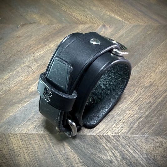Three-quarter view of a handcrafted 1.75" black leather two-piece cuff showcasing premium vegetable-tanned cowhide and nickel-plated steel hardware.