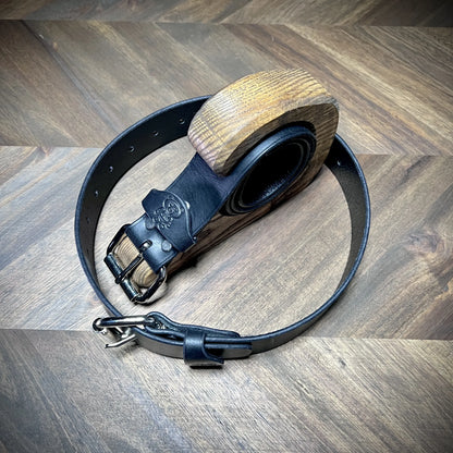 Macro close-up of Knotty Oso black leather restraint belts bench-crafted from 8oz vegetable-tanned leather, highlighting reinforced steel buckles.