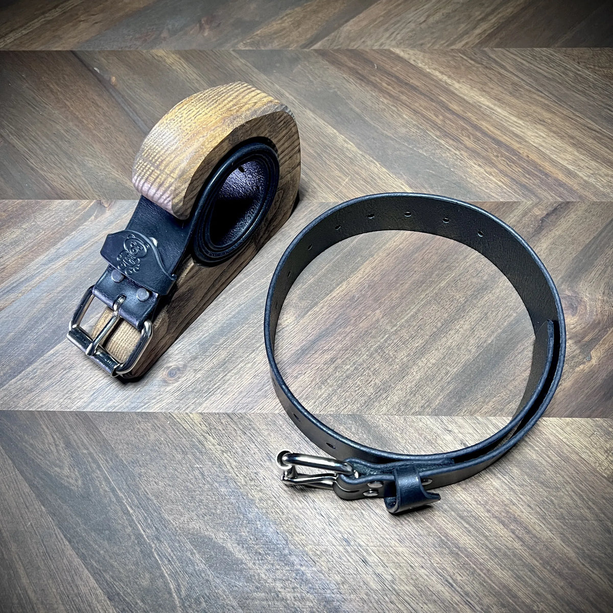 Hero view of handcrafted 1.5" black leather restraint belts showcasing premium vegetable-tanned cowhide, steel buckle hardware, and burnished edges.