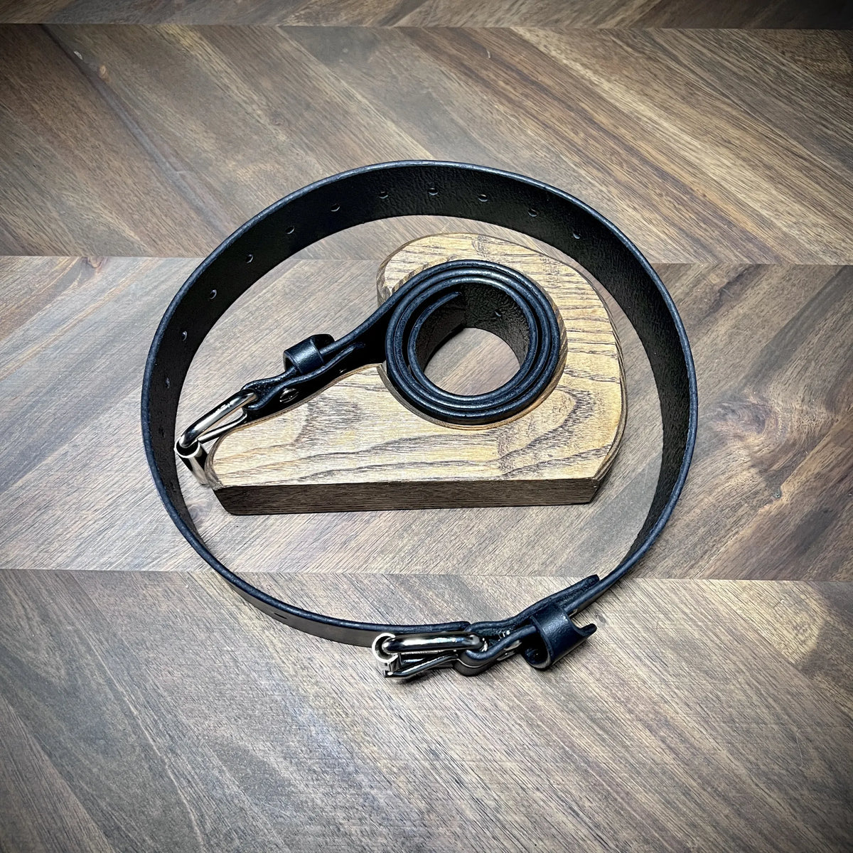 Studio view of 1.5" black leather restraint belts featuring structural 8oz leather and high-grade steel hardware styled as a subculture accessory.