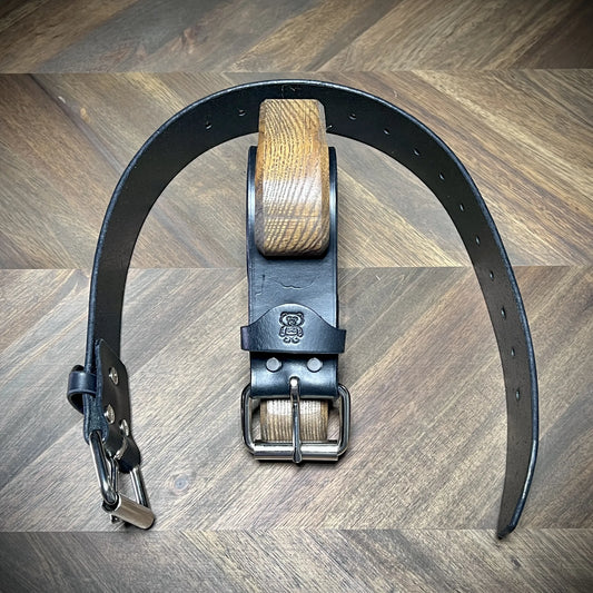 Front view of a pair of Knotty Oso restraints made from 1.75" black leather, showing uniform adjustment holes and reinforced steel buckle hardware.