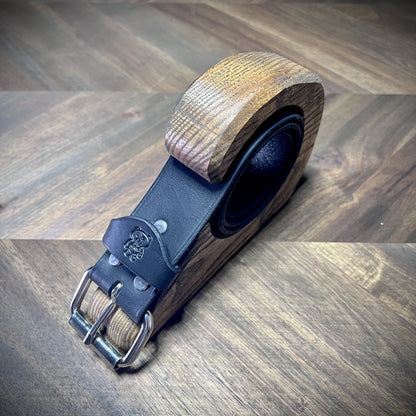 Hero tilt view of handcrafted 1.5" black leather belt highlighting a detailed debossed bear logo loop and high-grade steel roller buckle.