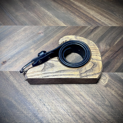 Studio craft view of a 1.5" black leather strap wrapped tightly inside a teardrop wooden workbench mold showcasing structural edge uniformity.