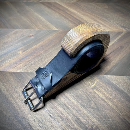 Oblique close-up view of a handcrafted 1.75" black leather restraint displaying premium vegetable-tanned cowhide and a heavy-duty steel roller buckle.
