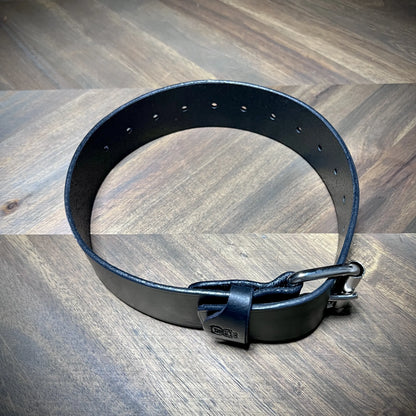 Rear view of a coiled 1.75" black leather belt revealing uniform inner grain texture, clean hole tracking, and durable edge dressing.