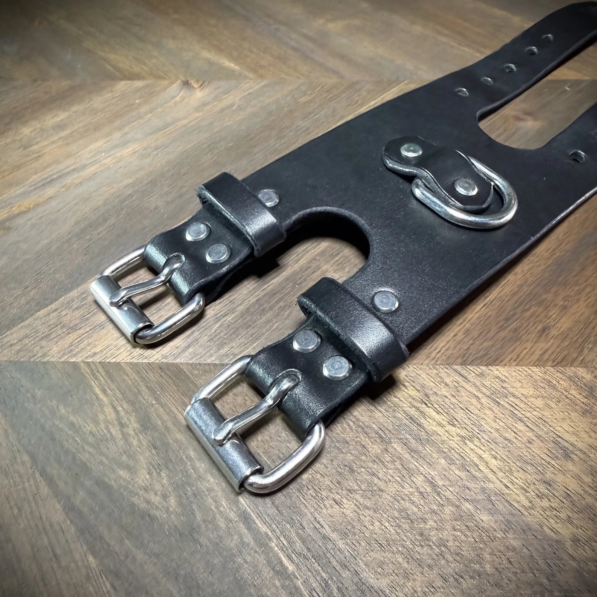 Detail macro view highlighting dual nickel-plated steel buckles riveted to a 3.5" black vegetable-tanned leather strap configuration.