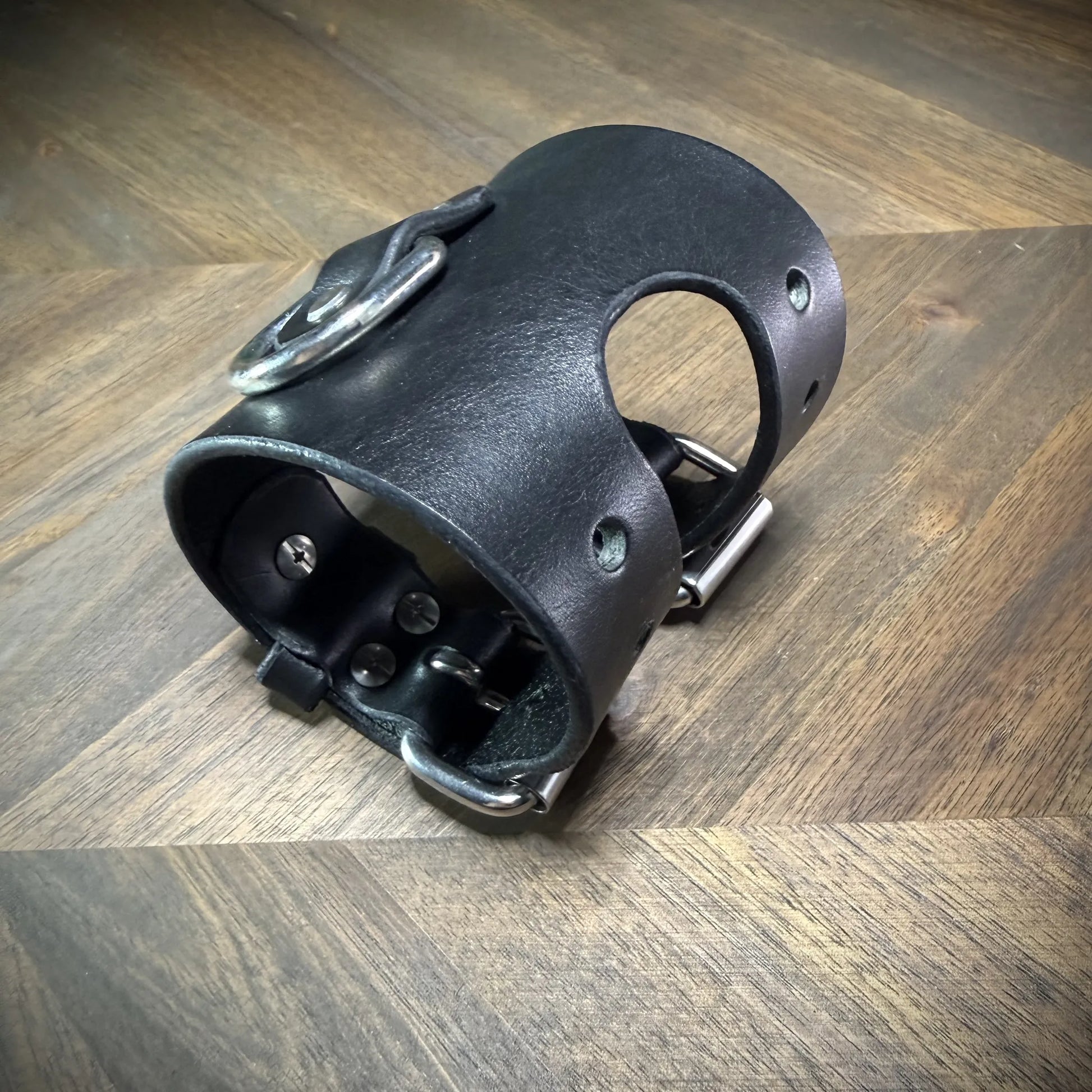 Front angled view of a closed 3.5" black leather cuff showcasing its clean burnished edge lines and high-stability steel D-ring anchor.