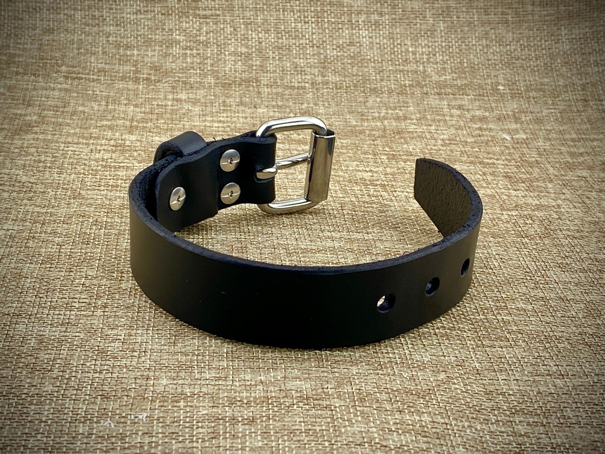 Profile perspective of a handcrafted 1" wrist cuff showcasing heavyweight 8oz American belt-weight leather, polished hardware surfaces, and sleek burnished edge construction.