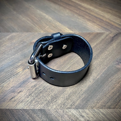 Interior view of a 1.5" black leather cuff highlighting flush rivet attachments and adjustment holes on the smooth grain side.