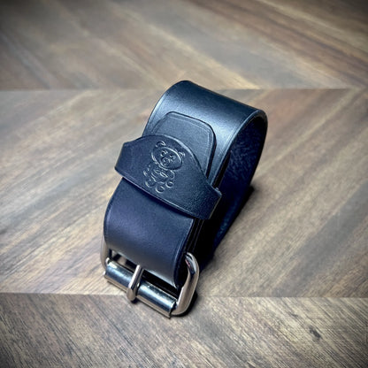 Profile view of a 1.5" black leather wrist cuff buckled securely onto itself, emphasizing its clean lines and edge treatments.