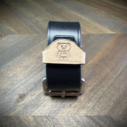 Front-facing view of a handcrafted 1.5" leather wrist cuff showcasing a natural leather belt keeper contrasted against a black strap layer.