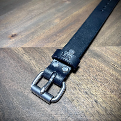 Macro close-up of a black leather cuff highlighting steel rivet alignment and durable strap loop engineering.