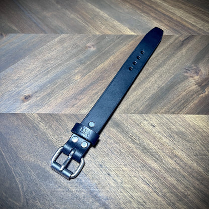 Full perspective layout of a black leather wrist cuff showcasing steel roller buckle hardware and clean adjustment hole styling.