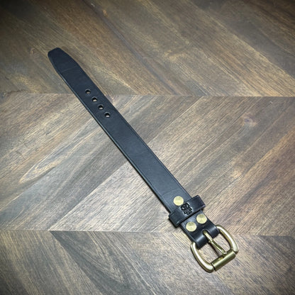 Hero tilt view of a handcrafted 1" black leather wrist cuff with a solid brass roller buckle and matching sunburst Chicago screws.