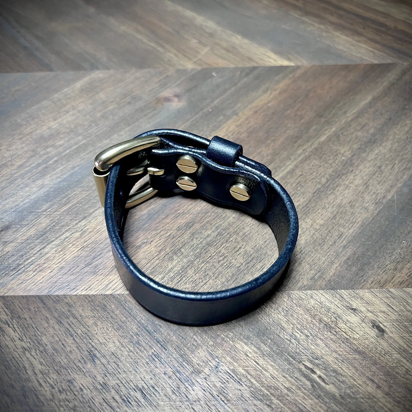 Studio craft view of a closed black leather strap highlighting the reverse fastening assembly with heavy-duty solid brass Chicago screws.