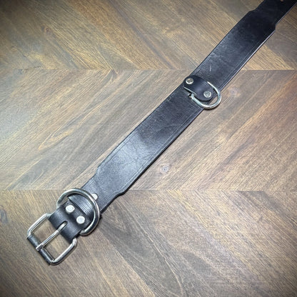 Top-down flat view of a 1.75" black leather collar revealing the full strap layout, roller buckle, belt keeper, and anchored D-ring.