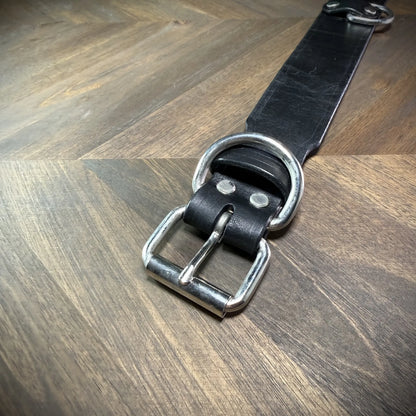 Top-down flat view of a 1.75" black leather collar revealing the full strap layout, roller buckle, belt keeper, and anchored D-ring.