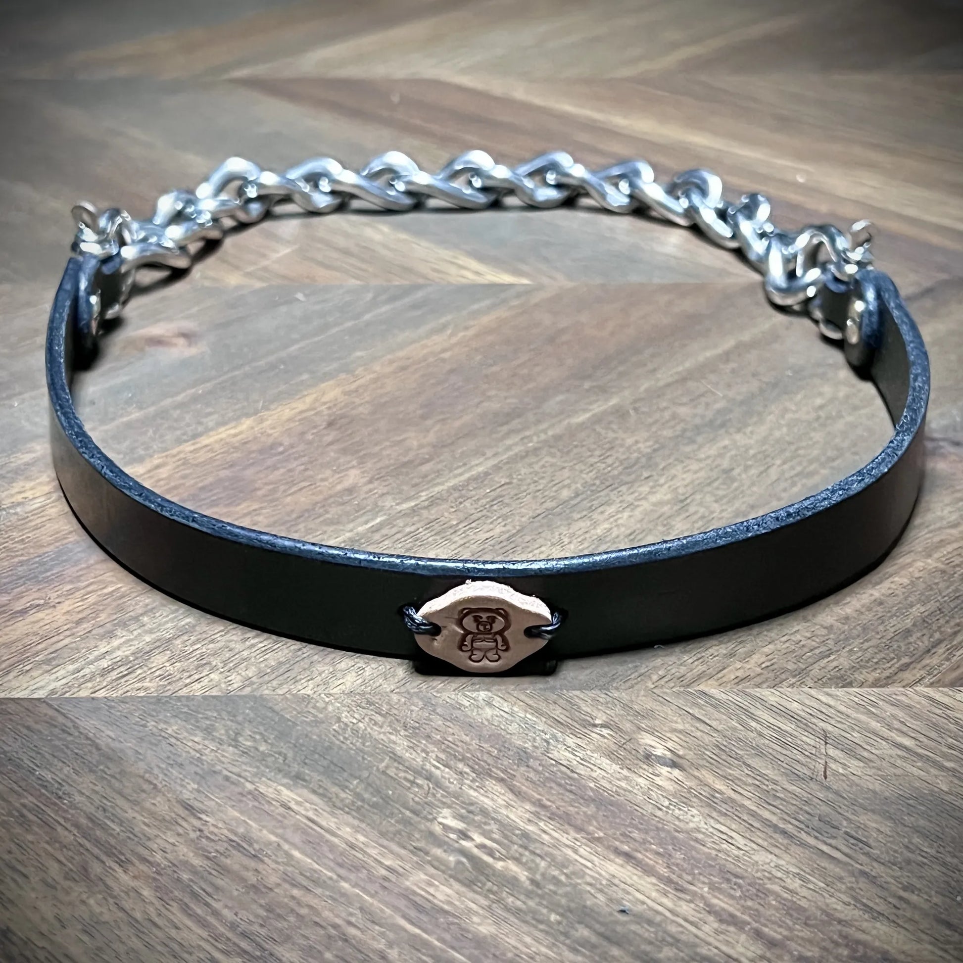 Front reveal of a 0.75" black leather subculture collar with heavy industrial nickel-plated steel chain and centered vegetable-tanned logo tag.