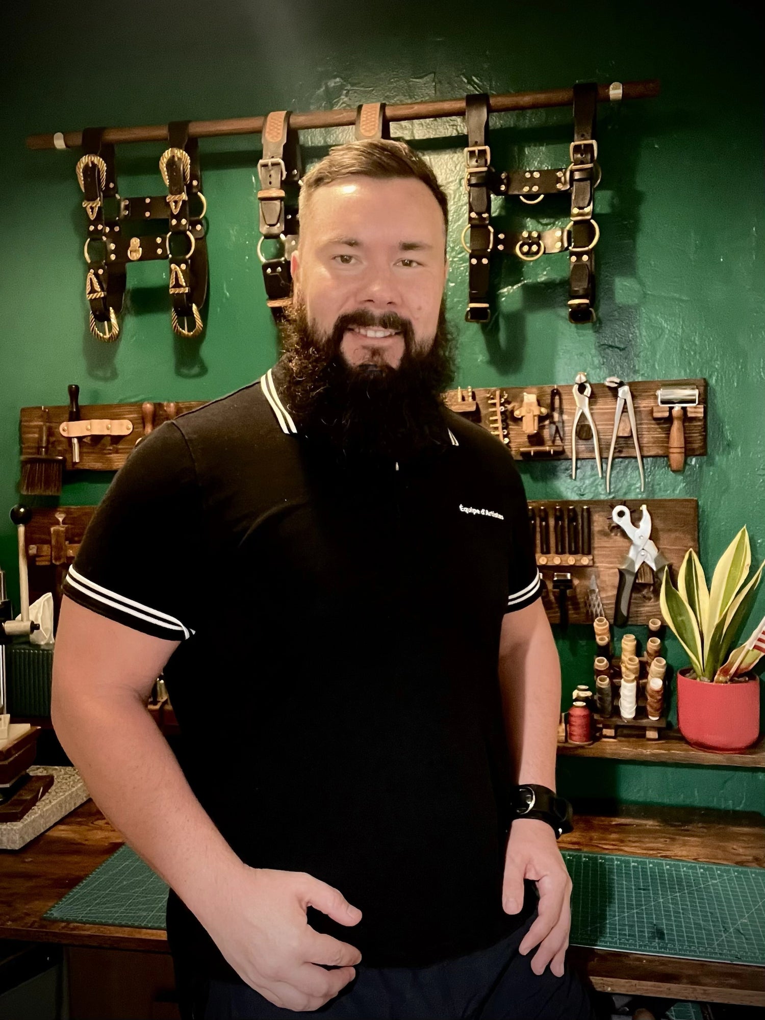 Portrait of the artisan leathercraft master standing in front of organized workshop tool racks and display mounts inside the Miami Beach studio