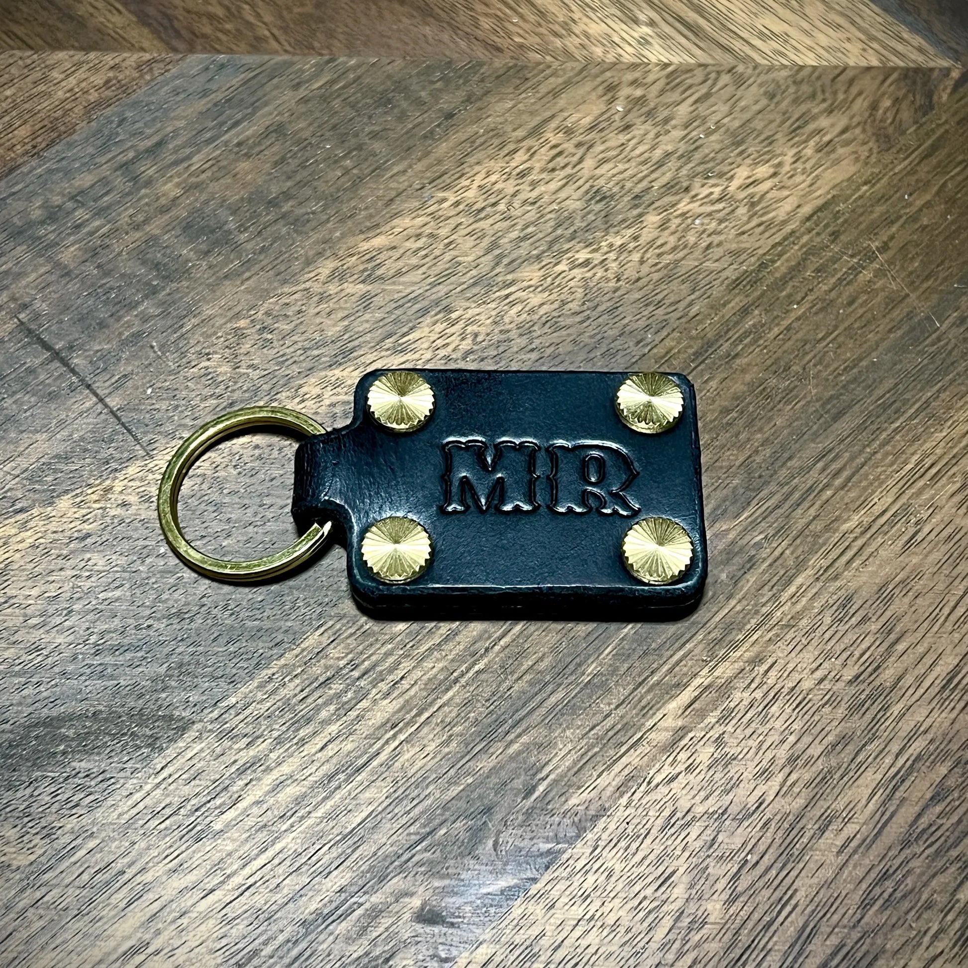 Personal initial embossed black leather keychain paired with solid brass hardware.