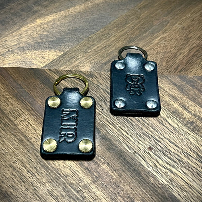 Handmade black leather keychains featuring custom initials and bear stamp with steel and brass hardware.
