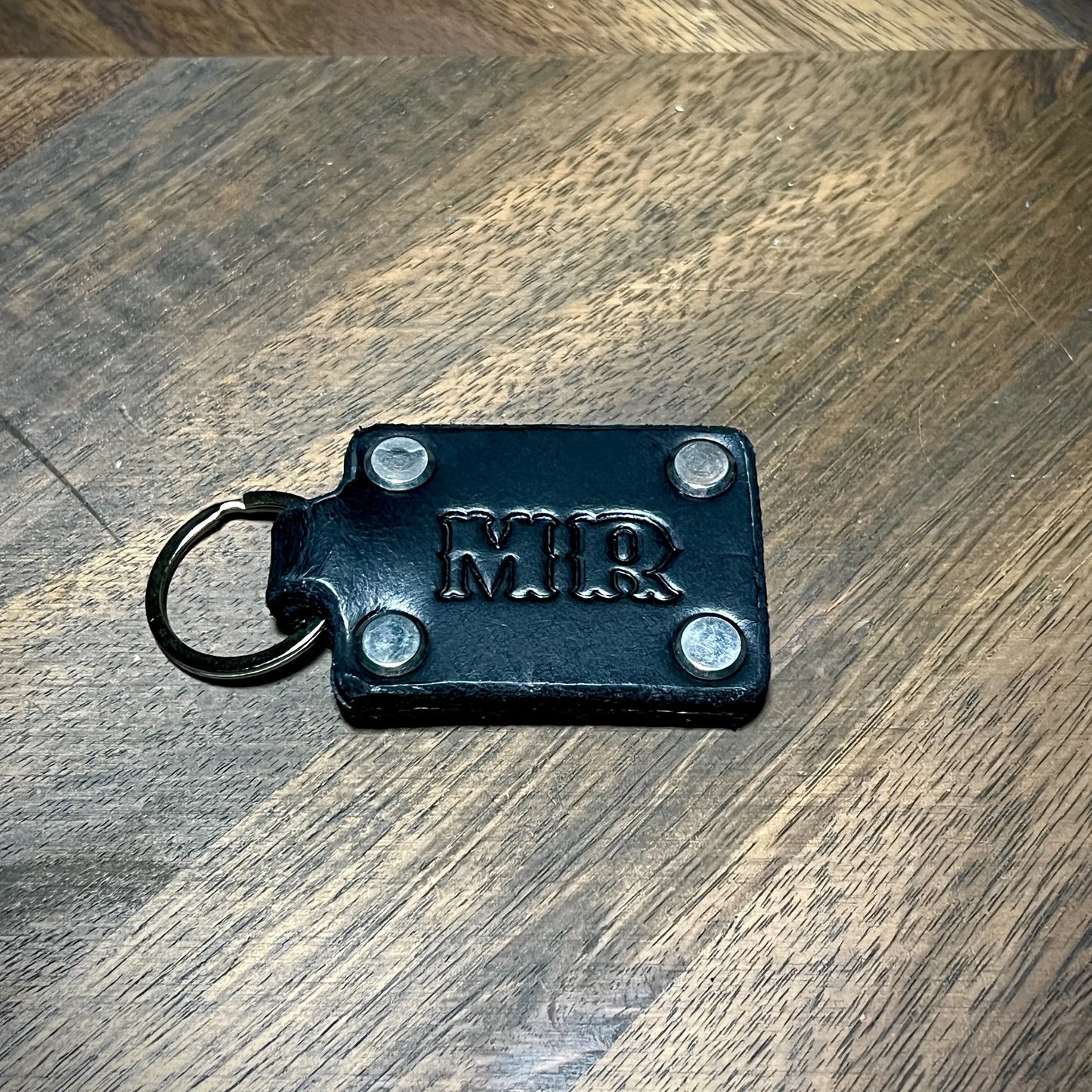 Custom initialed black leather keychain with stainless steel hardware and four corner rivets.