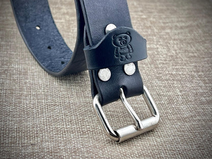 Black leather belt with silver buckle on a textured surface